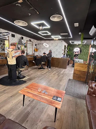 Interior de la barbería, con sillones, espejos y zona de espera.
